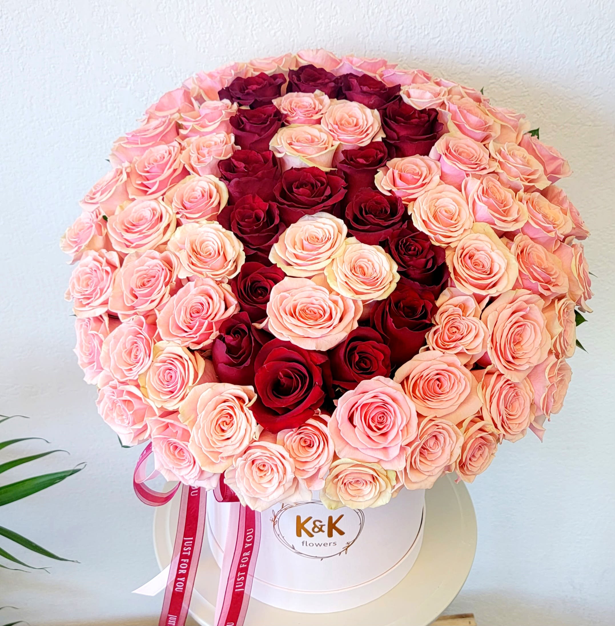 Round bouquet of pink and red roses in a white hat box