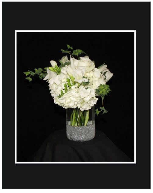 White floral arrangement in a clear vase with a glittery base