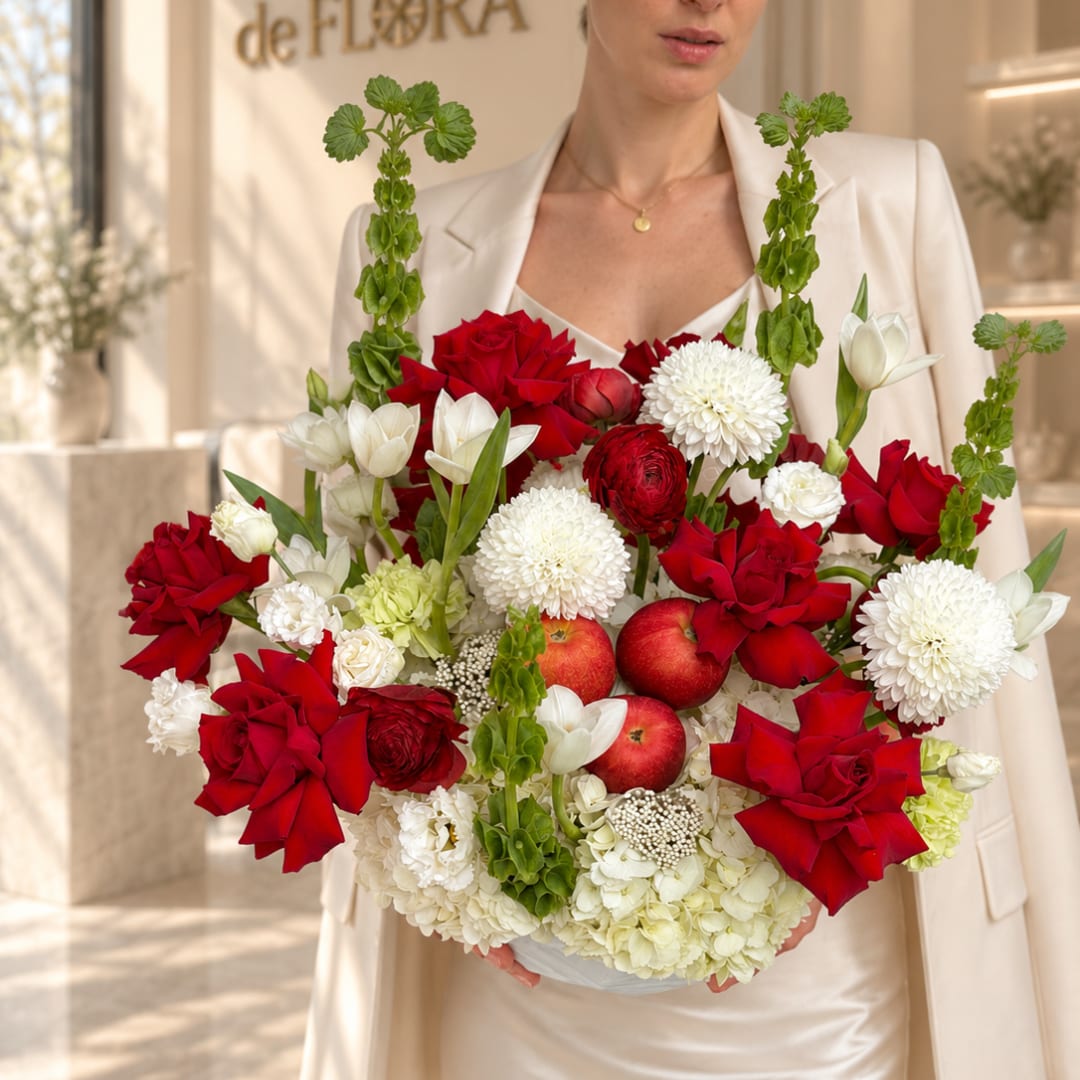 Woman holding a bouquet of red and white flowers with apples