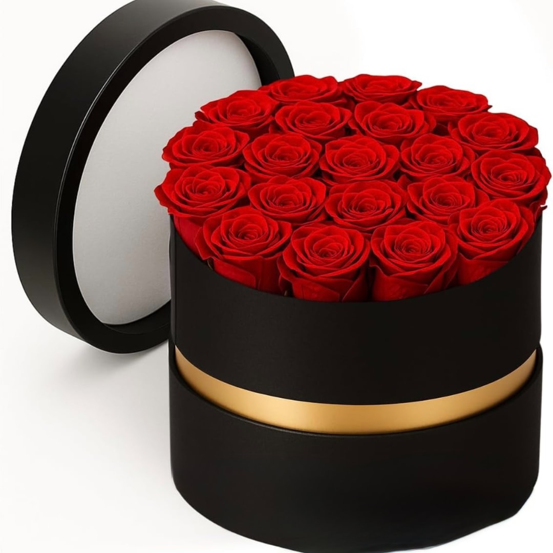 Red roses arranged in a round black hat box with a gold band
