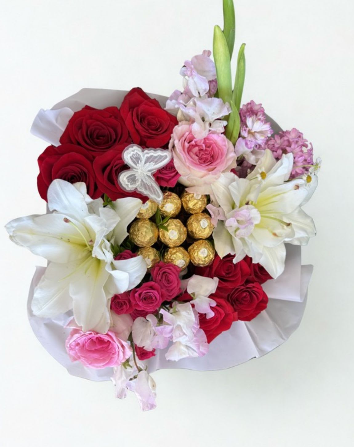 Enchanting Bloom Box - A romantic floral box featuring red roses, blush blooms, elegant white lilies, and golden chocolates, beautifully arranged for a luxurious and heartfelt gift.