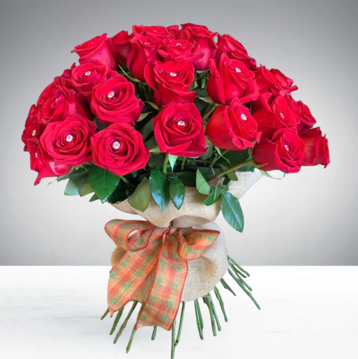 Scarlet Elegance by D'Lily's Flowers  - A beautiful bouquet of red roses with sparkling rhinestones, wrapped in burlap and finished with a charming bow. Perfect for any special occasion. Disclaimer: This is a wrapped bouquet. No Vase is Included. 