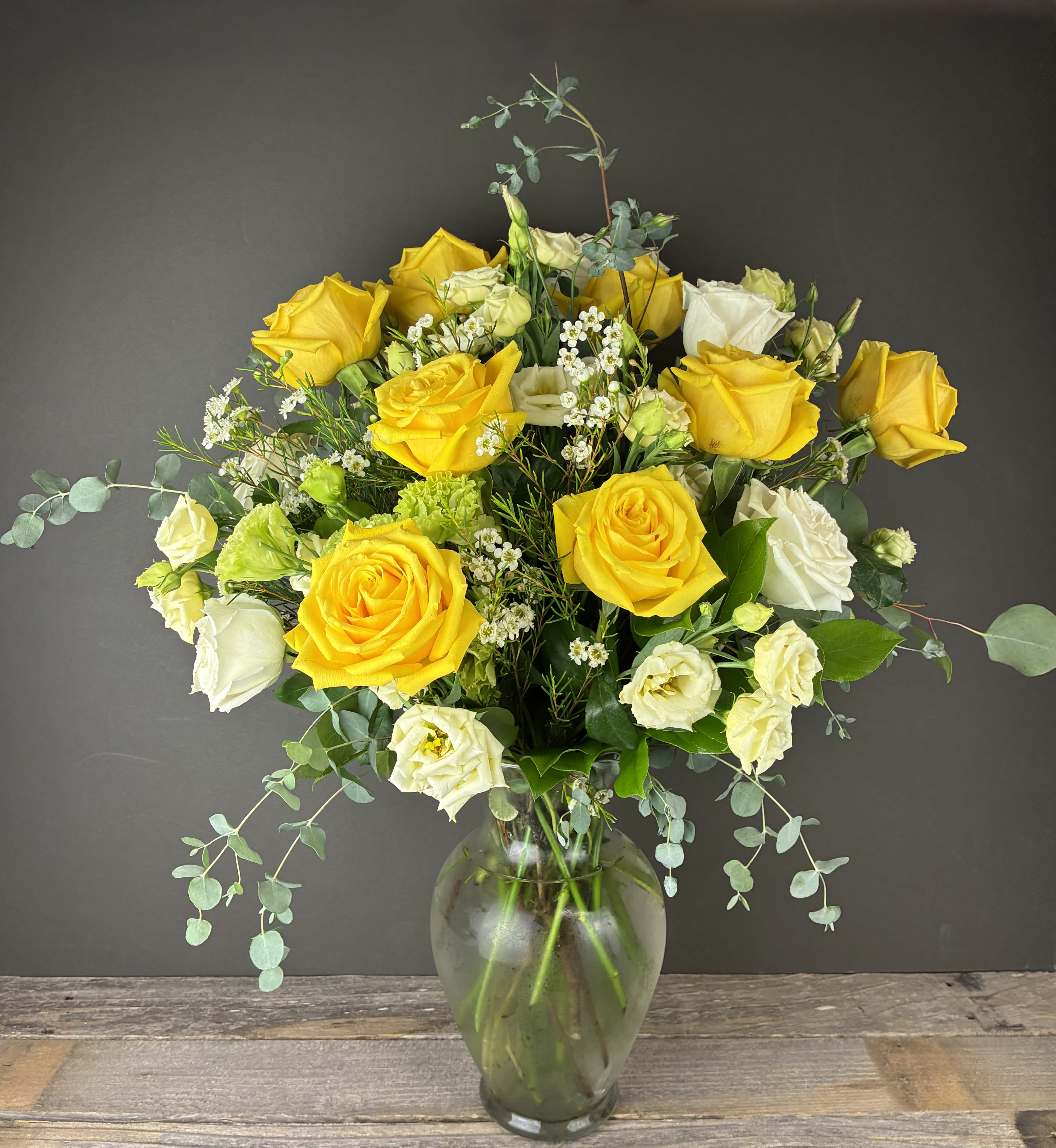 Yellow and white roses in a clear glass vase with airy filler flowers