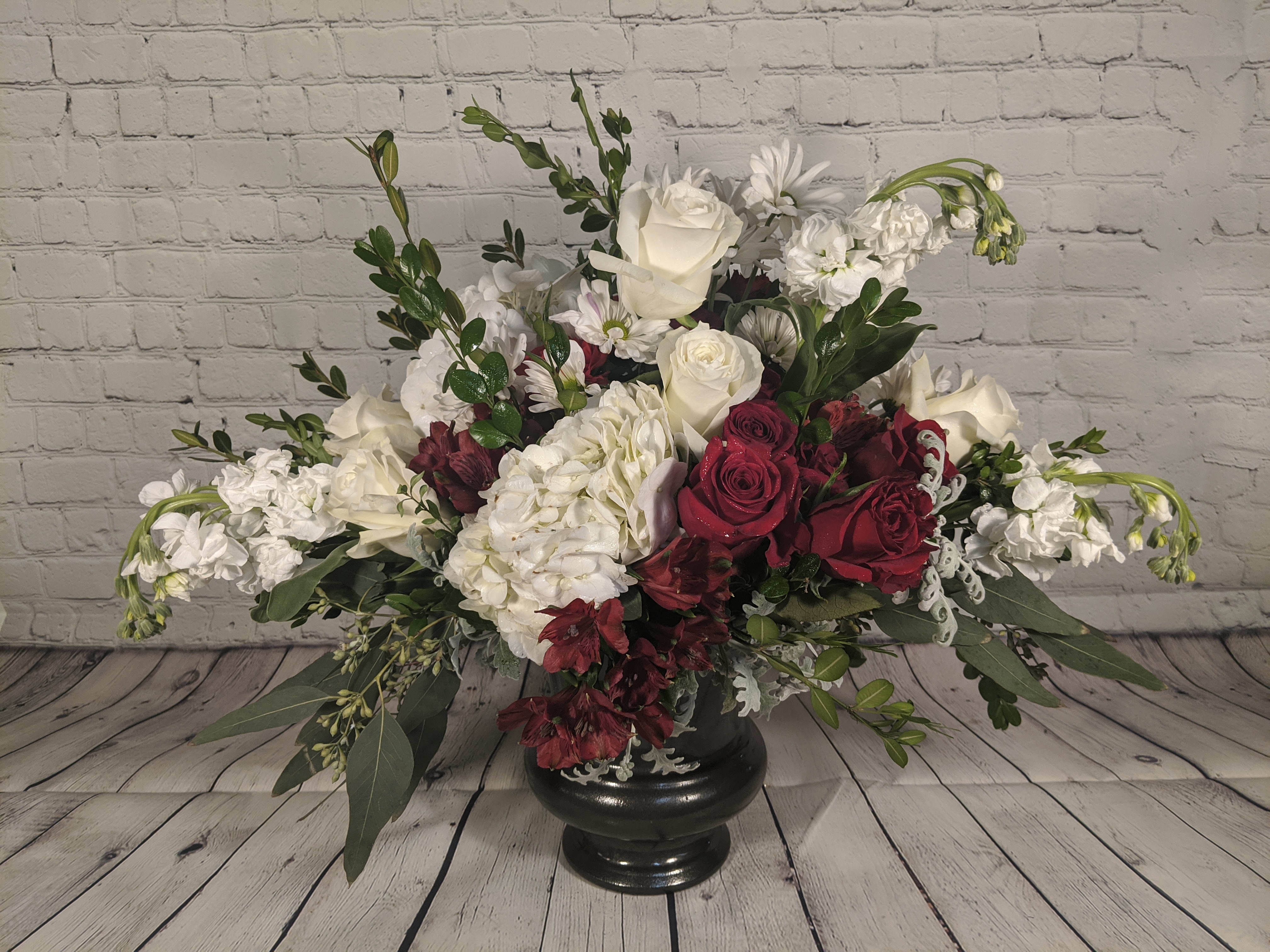 Large floral arrangement of white and deep red flowers in a black vase