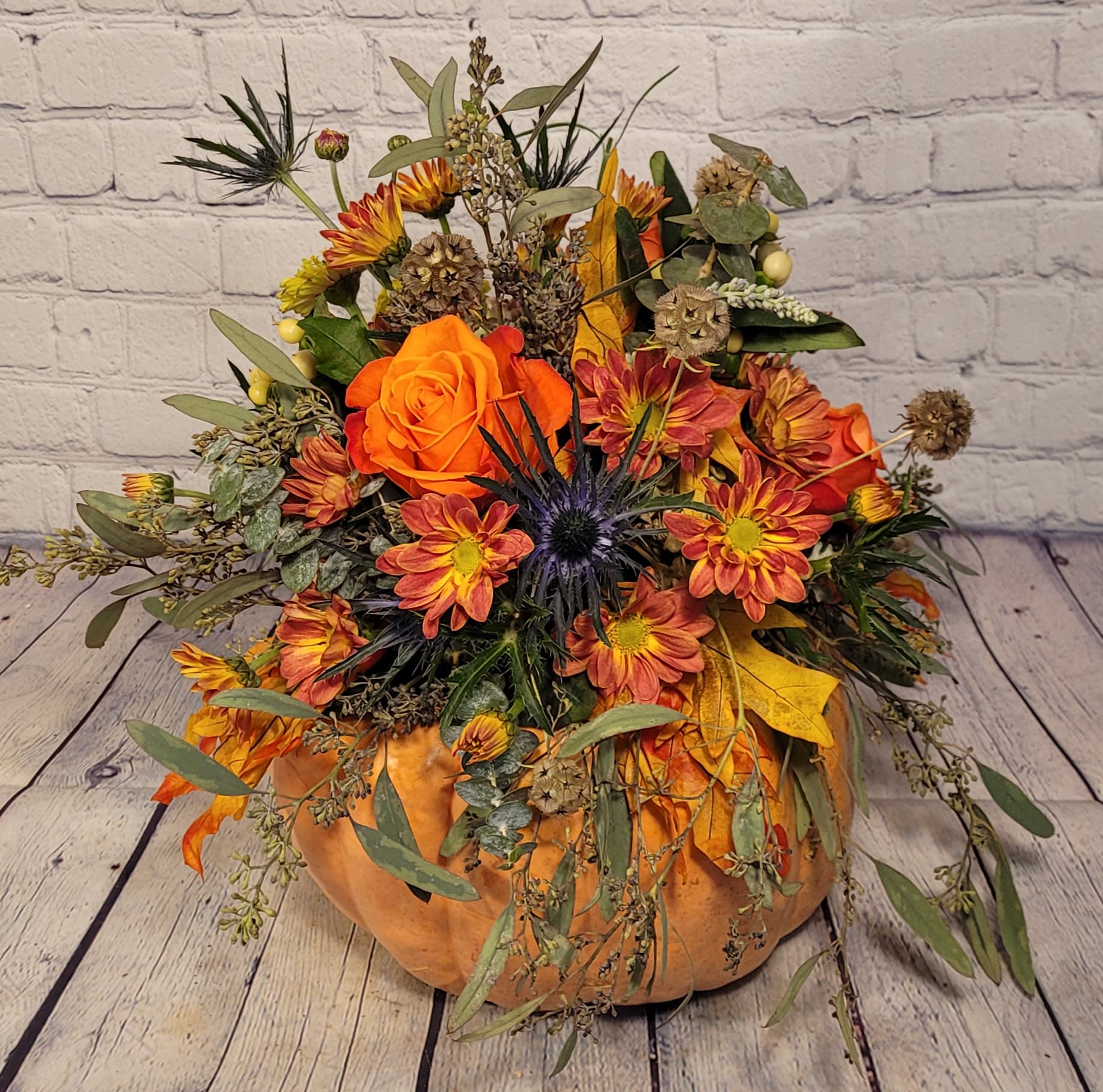Gourdgeous  - This bouquet of flowers is arranged on top of a real locally grown pumpkin*. Flowers for this Gorgeous Gourd Bouquet may include, but are not limited to; roses, chrysanthemums, daisies, thistle, spray roses, hypericum, grivellia, seeded eucalyptus, and other fall accents. *Pumpkin color dependent upon availability (orange, white, or green)