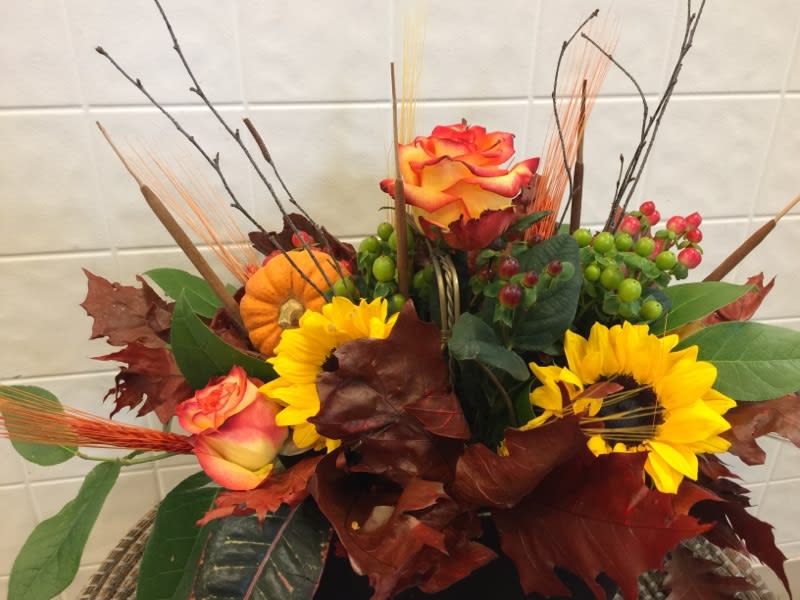 Astounding Arrangement - To get this look, arrange sunflowers, cockscomb, calla , pin cushion protea, orange roses, and seeded eucalyptus and eucalyptus gunnii in a low, rustic-style vase filled with a moistened block of floral foam.