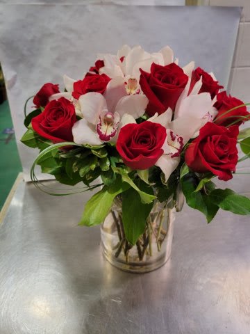 Red roses and white orchids arranged in a clear glass vase