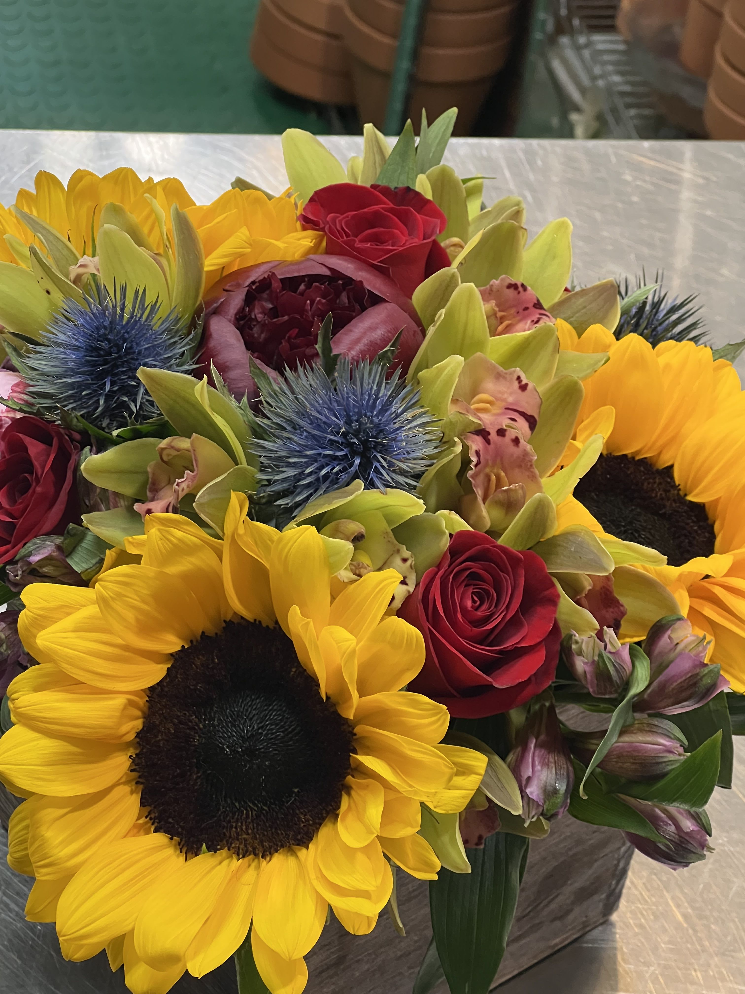 Bouquet with sunflowers, red roses, and blue thistle