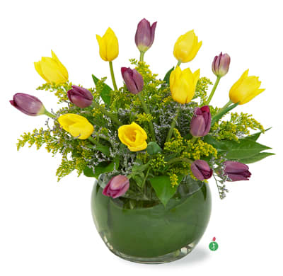 Yellow and purple tulips in a round glass vase