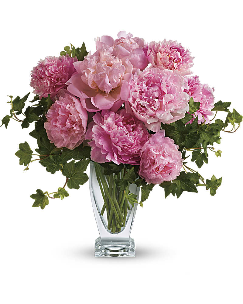 Pink peonies in a clear glass vase with trailing ivy
