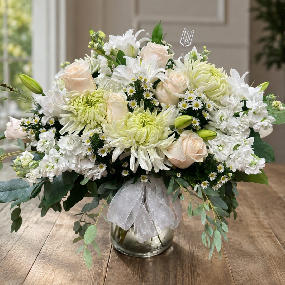 White and pale peach floral arrangement in a glass vase