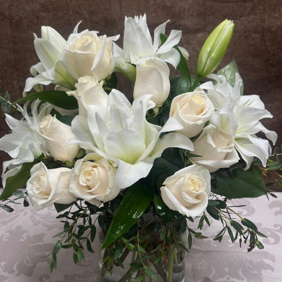 White roses and lilies arranged in a glass vase
