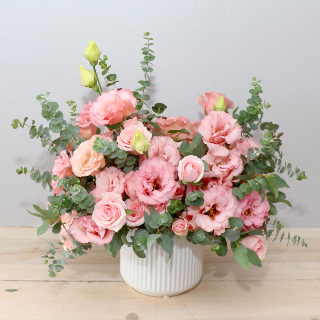 Pink roses and lisianthus in a white ribbed vase