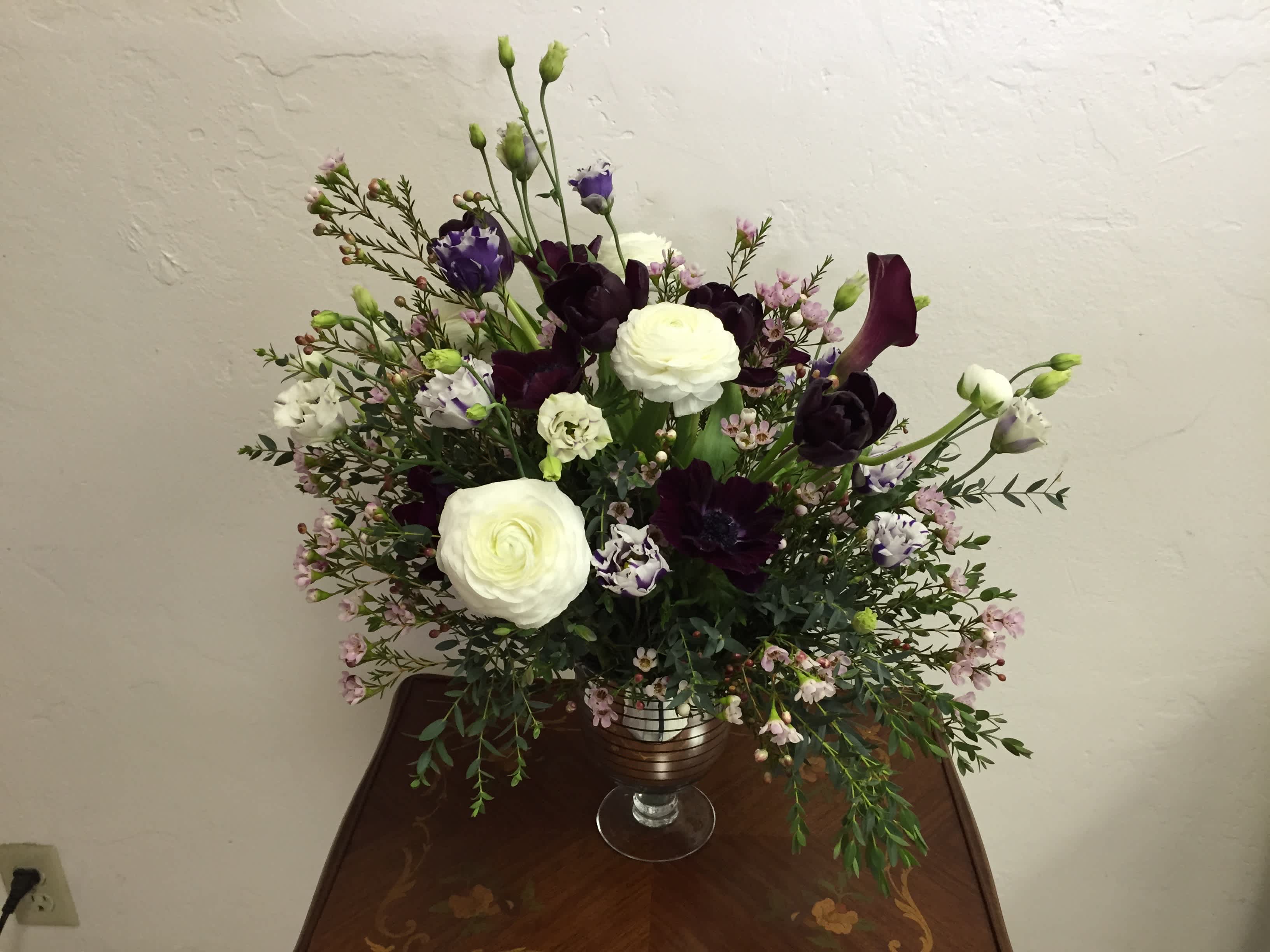 White and dark purple floral arrangement in a glass vase