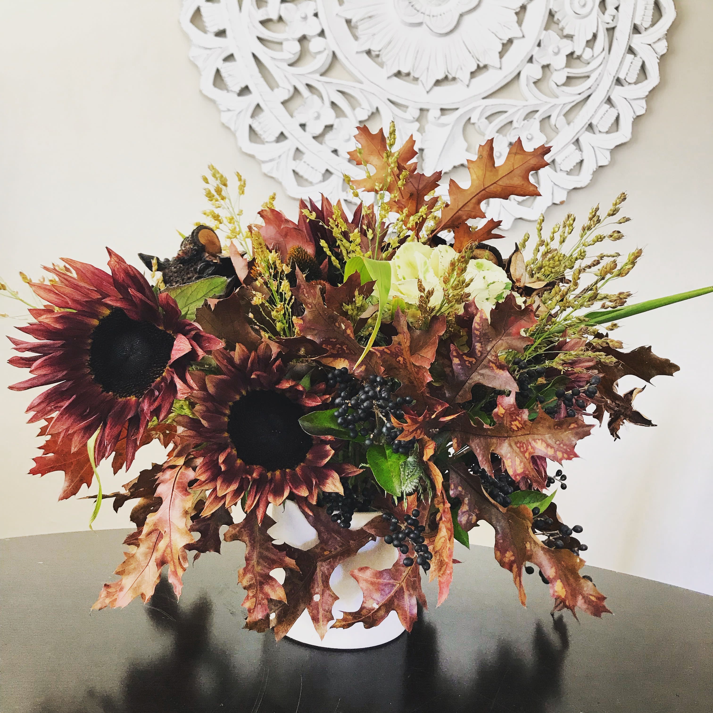 Autumn bouquet with dark sunflowers in a white vase