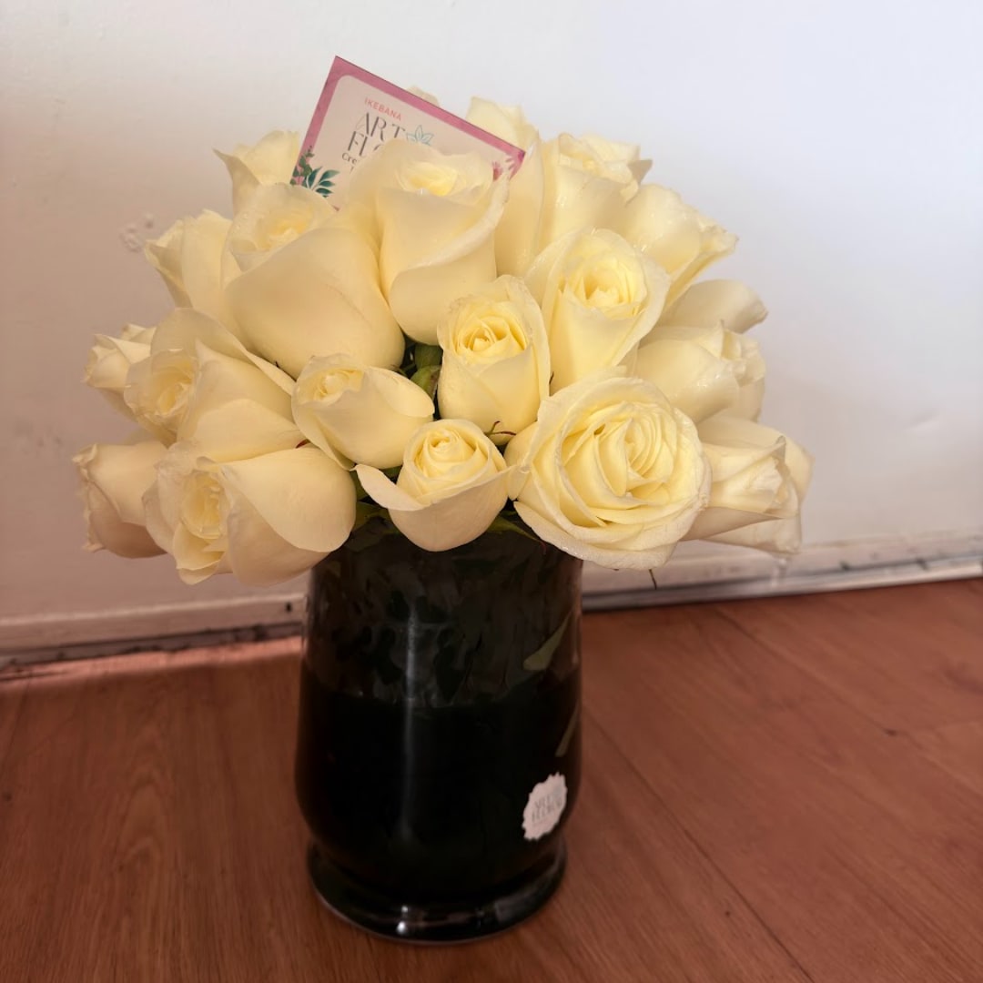 Bouquet of cream roses in a dark glass vase