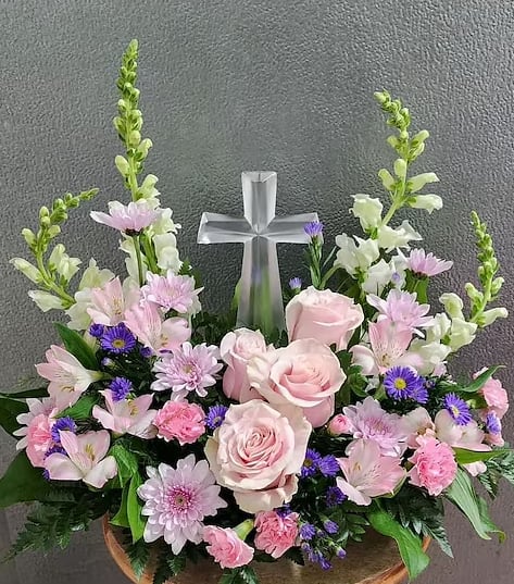 Pink and white floral arrangement with a silver cross centerpiece