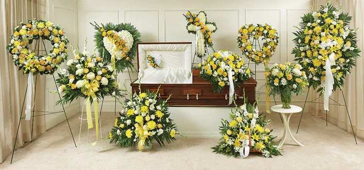 Yellow and white funeral floral tributes arranged around a casket