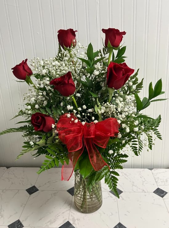 Red roses with baby's breath in a glass vase and red bow