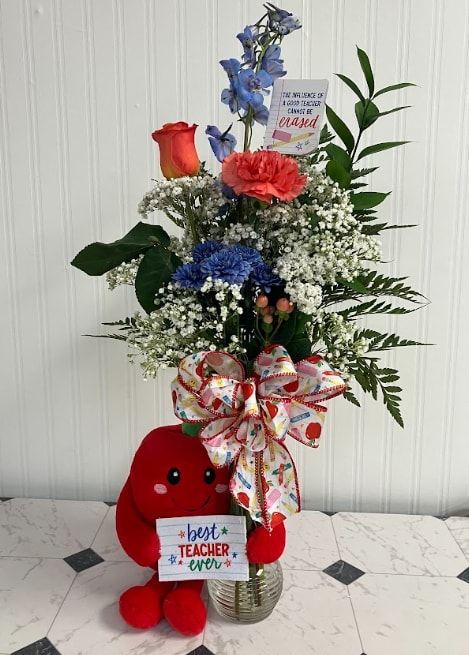 Tall mixed flower arrangement with a plush teacher bear and gift sign in a glass vase