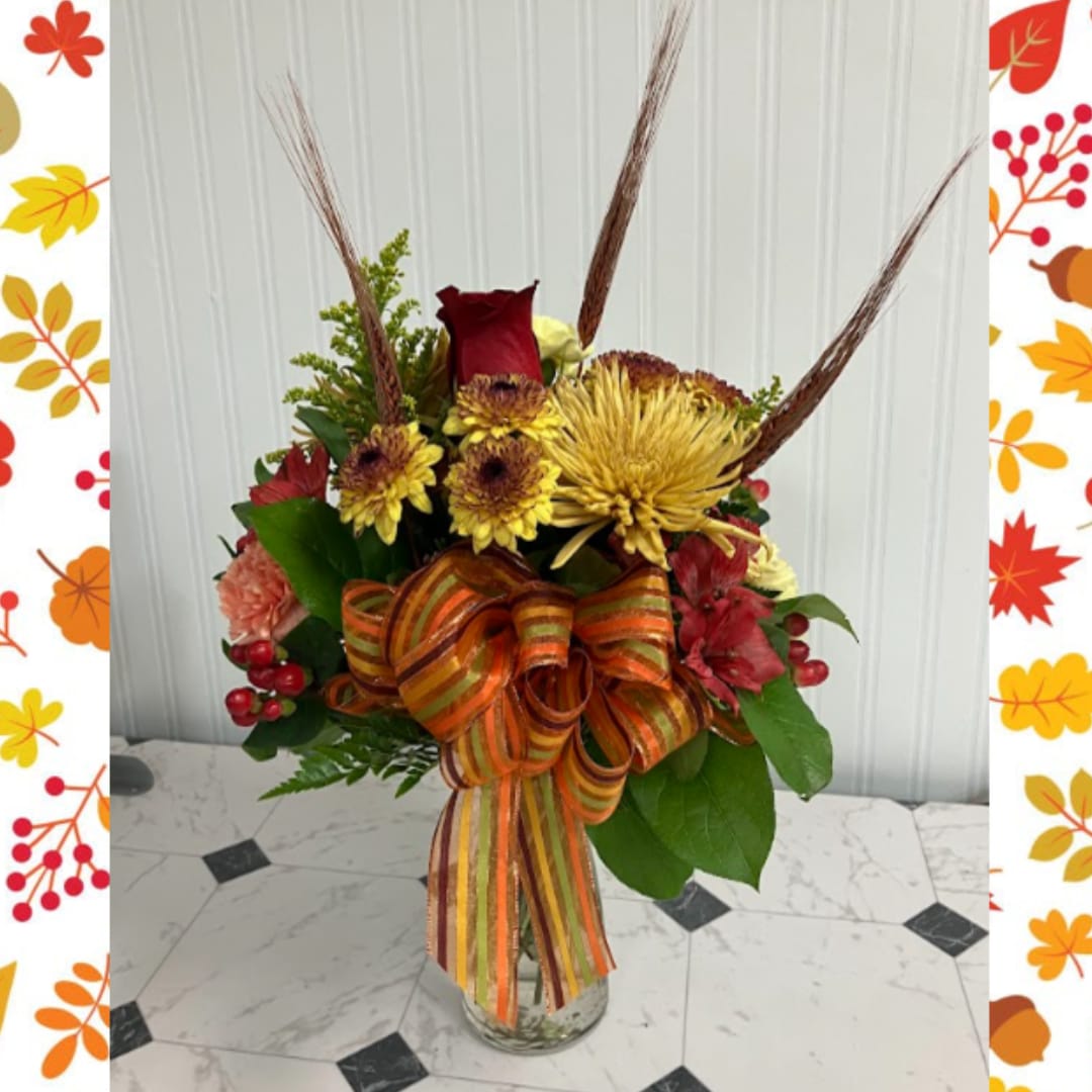 Autumn bouquet with red and yellow flowers in a glass vase and striped ribbon