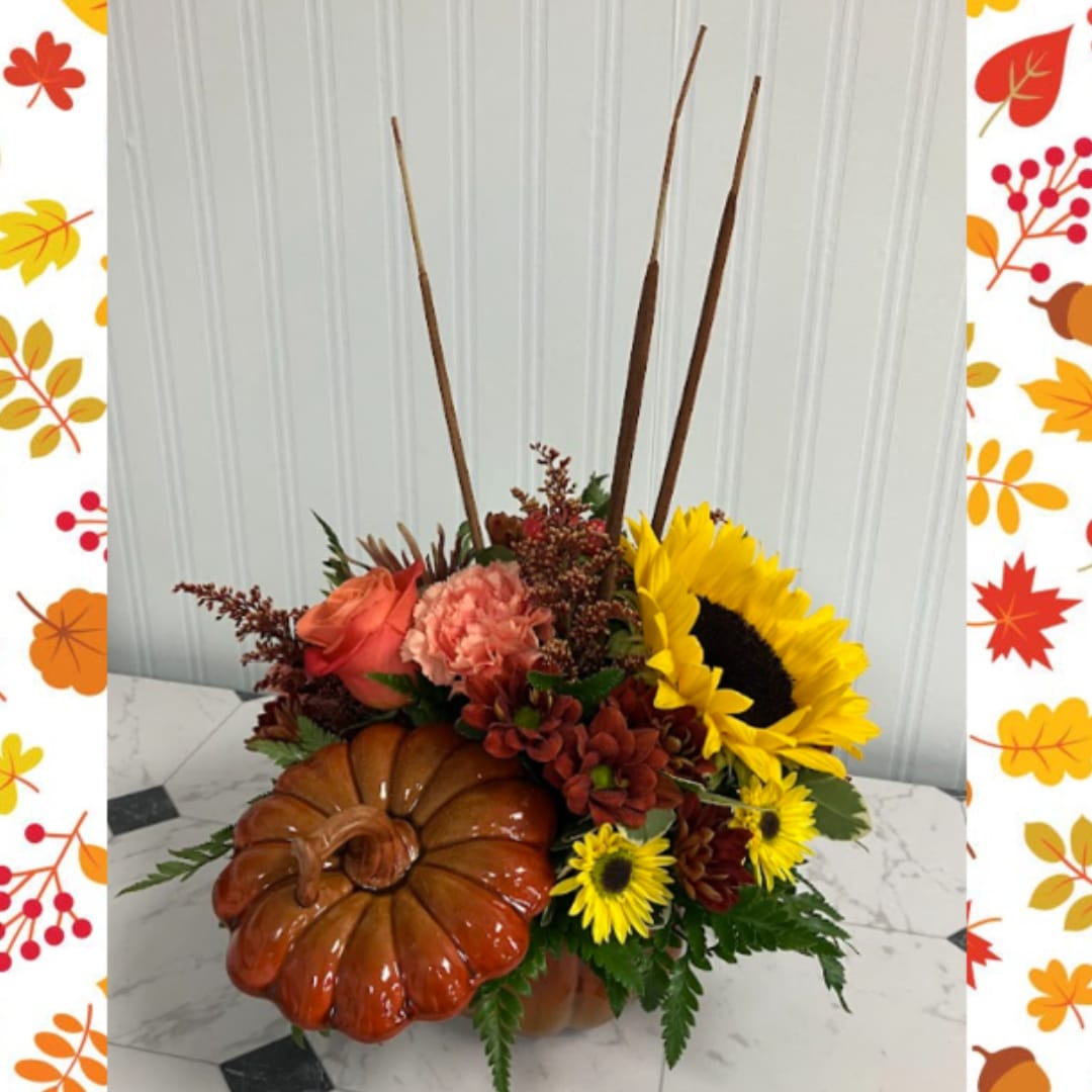 Fall floral arrangement with sunflowers, roses, carnations, and a pumpkin container