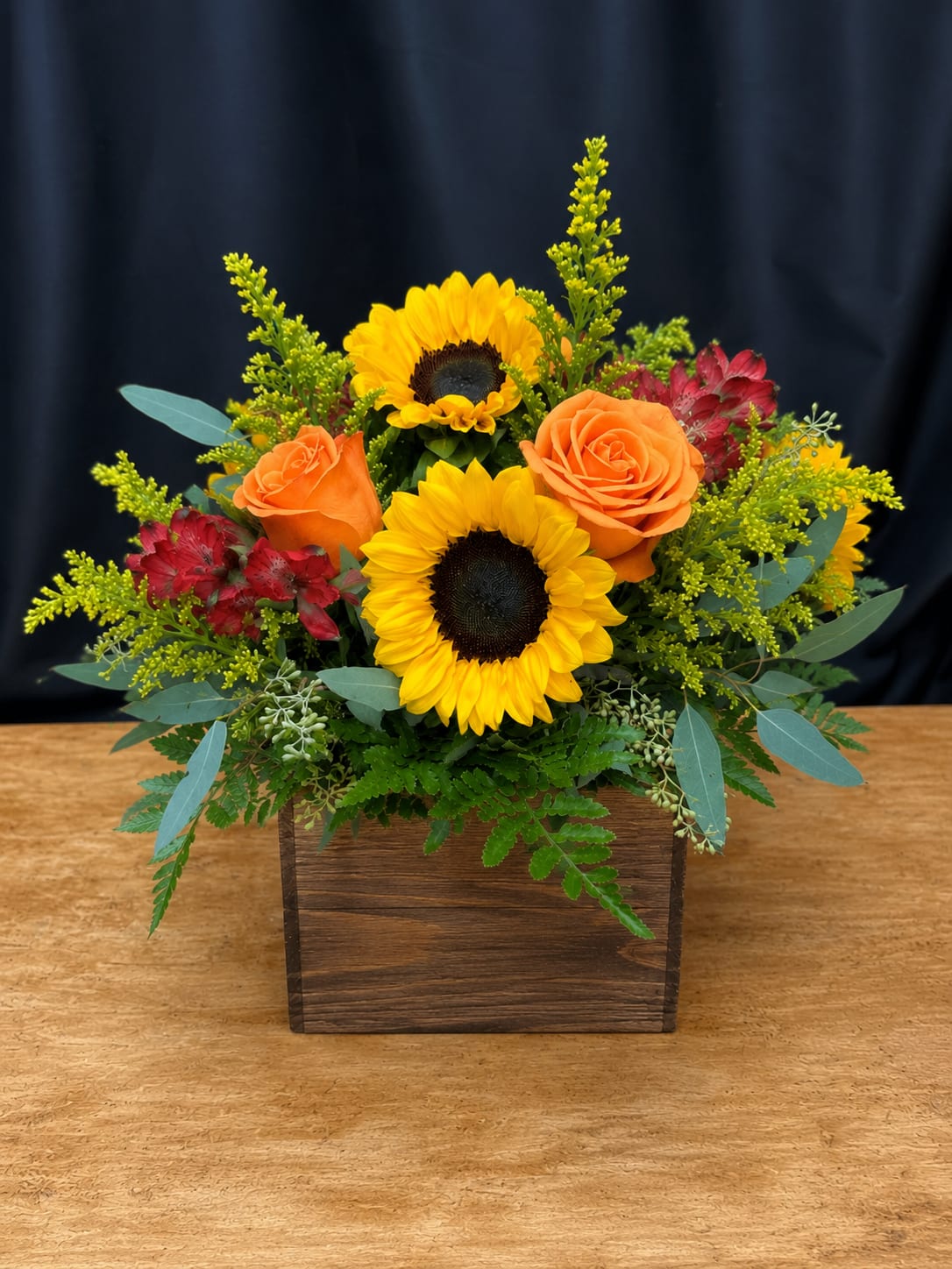Sunflower and orange rose arrangement in a wooden box