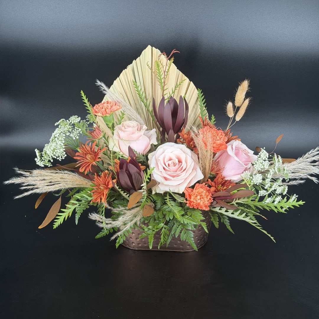 Mixed floral arrangement in a brown vase with pink roses and orange blooms