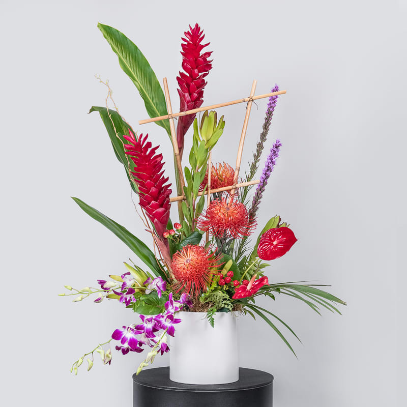 Tropical flower arrangement in a white cylindrical vase