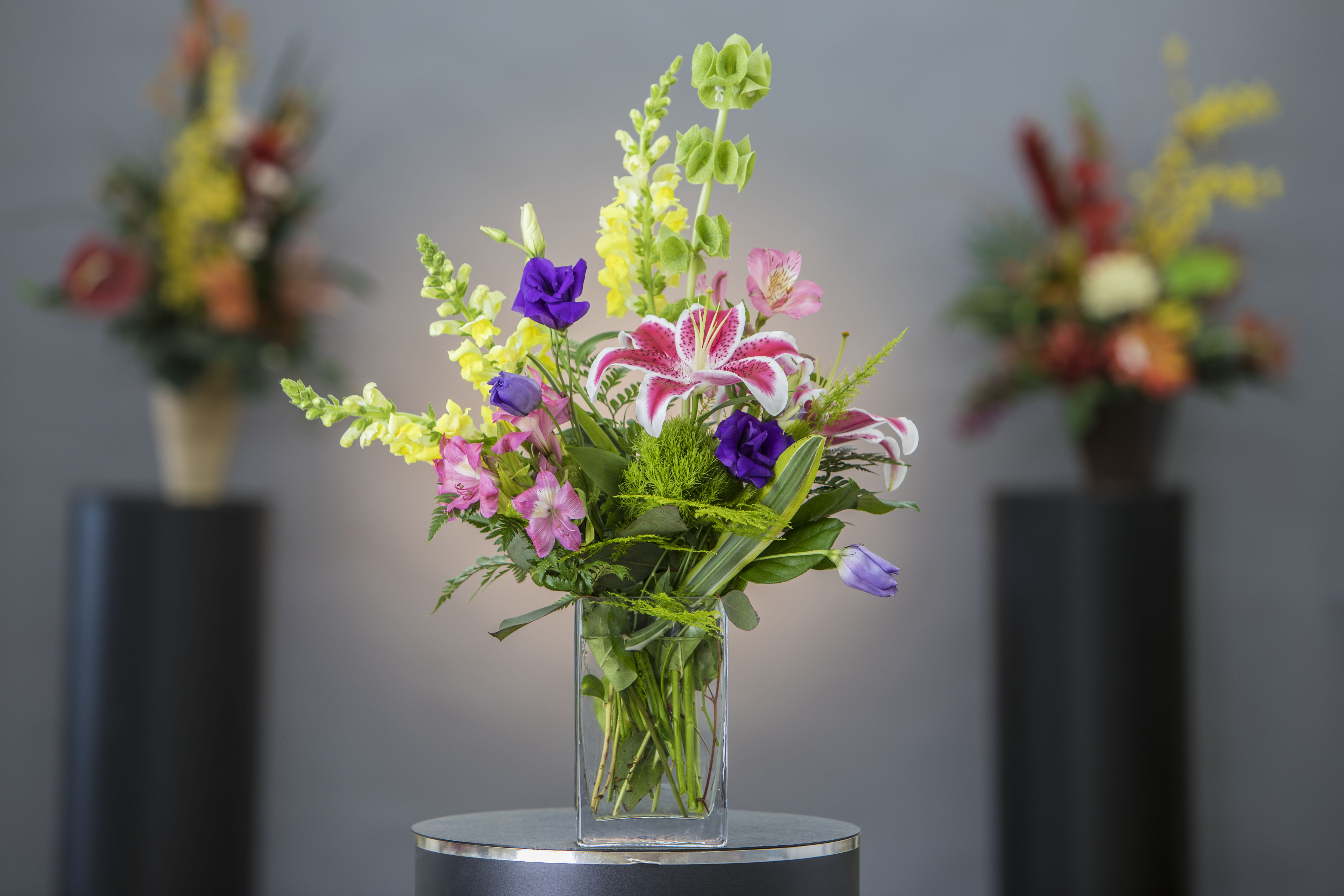 Mixed bouquet in a clear glass vase with pink, yellow, purple, and white flowers