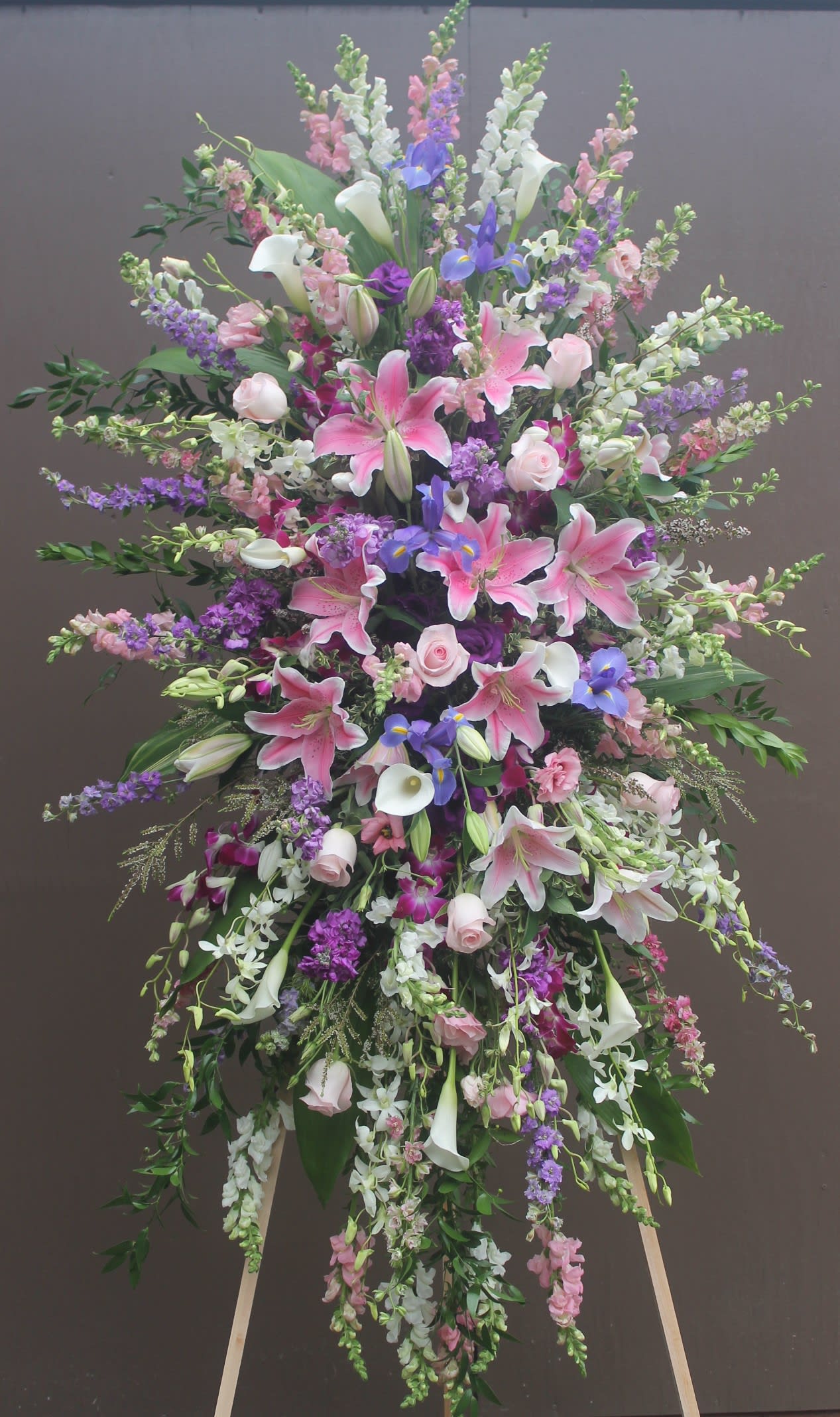 Large standing floral spray with pink lilies, white calla lilies, and purple blooms