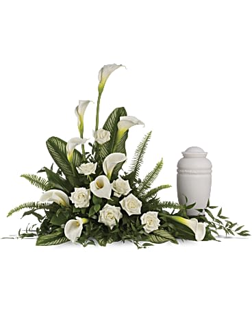 White calla lilies and roses arranged beside a white urn