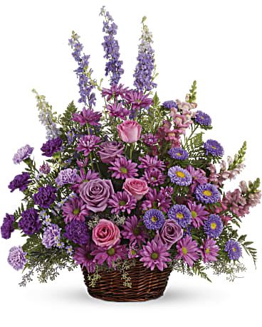 Purple and pink mixed flower arrangement in a wicker basket