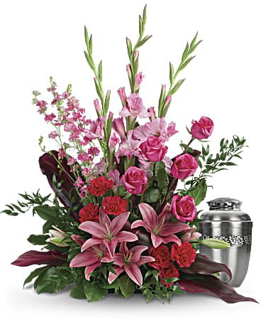 Pink lilies and roses arranged beside a silver urn
