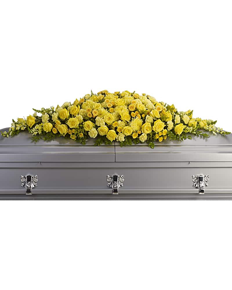 Yellow floral casket spray on a gray casket