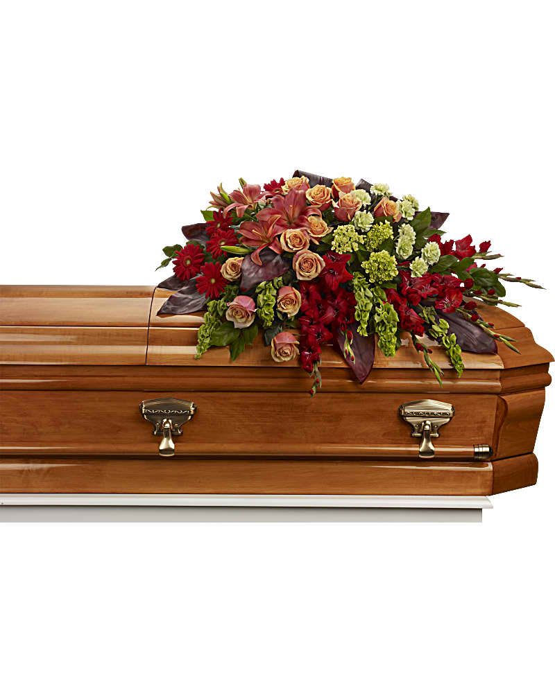 Casket spray with red and peach flowers on a wooden casket