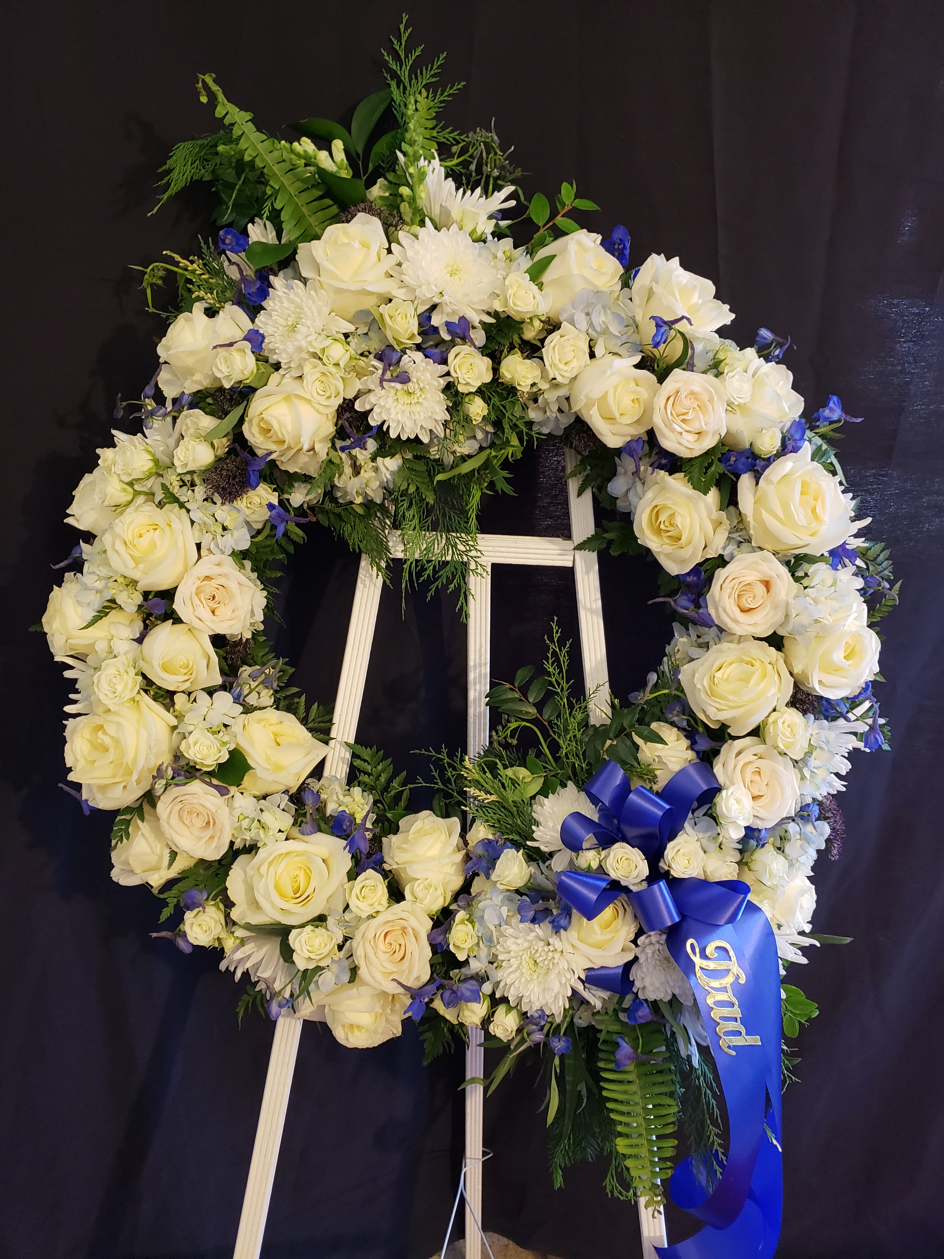 Circle of Memories Wreath in white - White Roses, Cushion Chrysanthemums and Blue Hydrangea create a stunning display to honor  the life of a wonderful person.