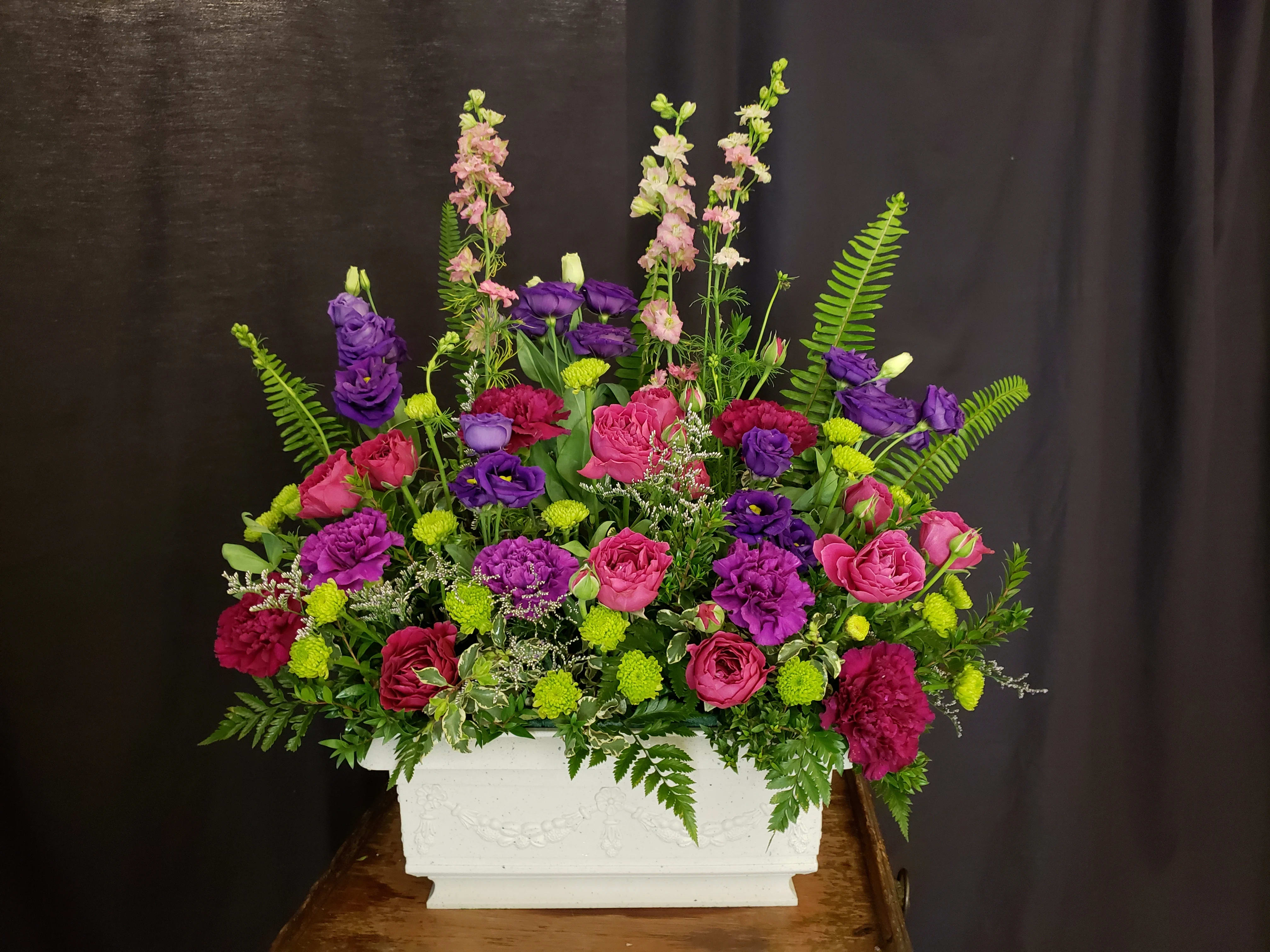 Pink and purple floral arrangement in a white rectangular planter