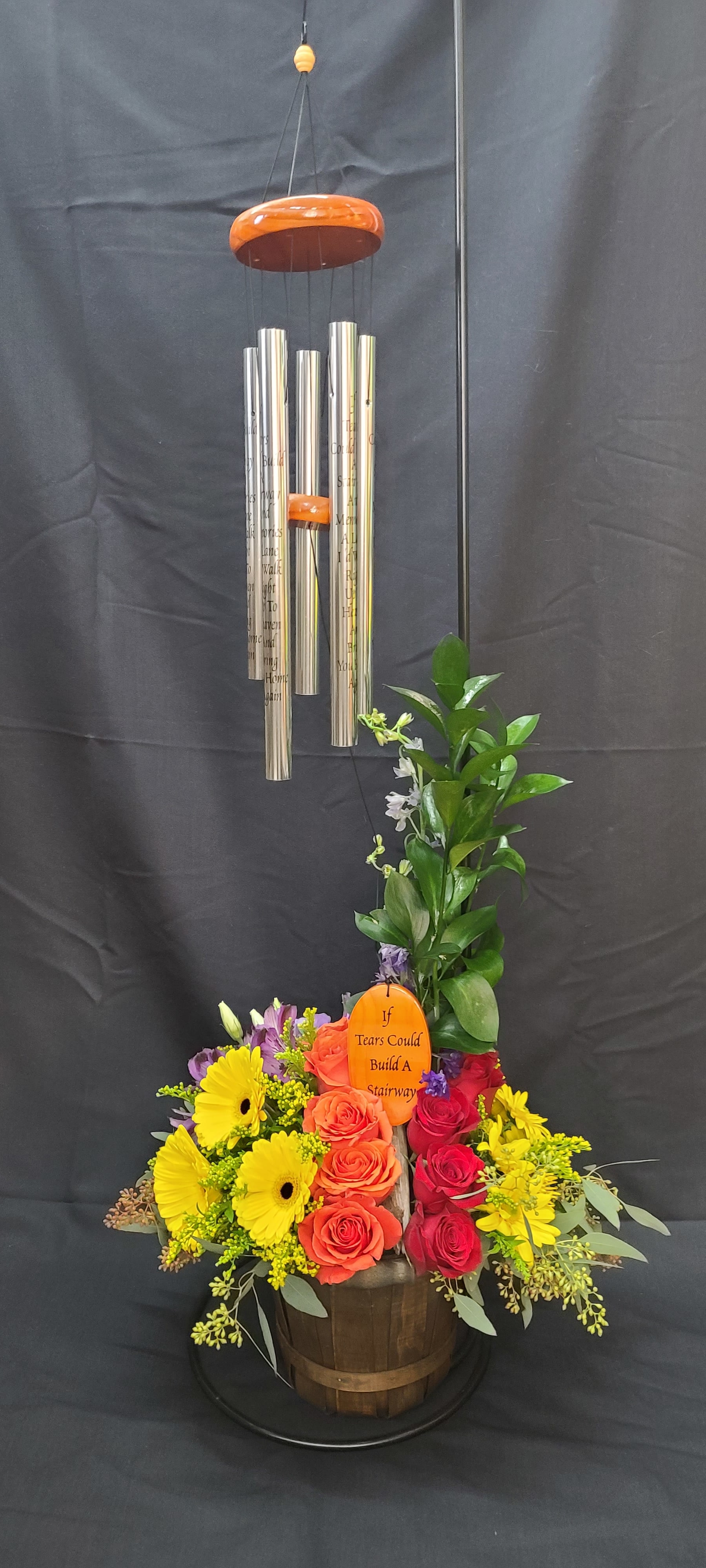 Colorful floral arrangement with wind chimes in a wooden basket
