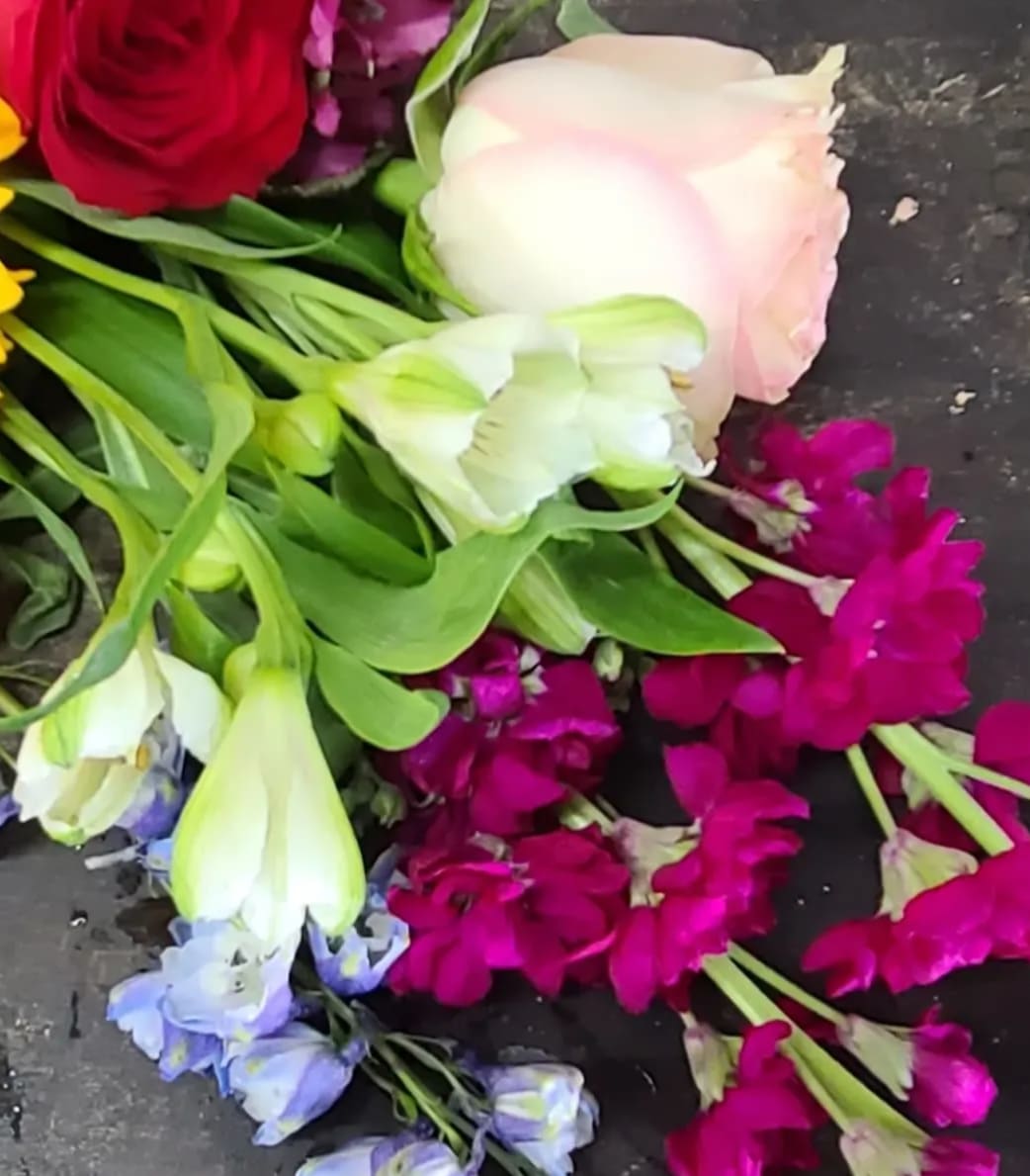 Mixed bouquet with roses, tulips, and purple blooms on a dark surface