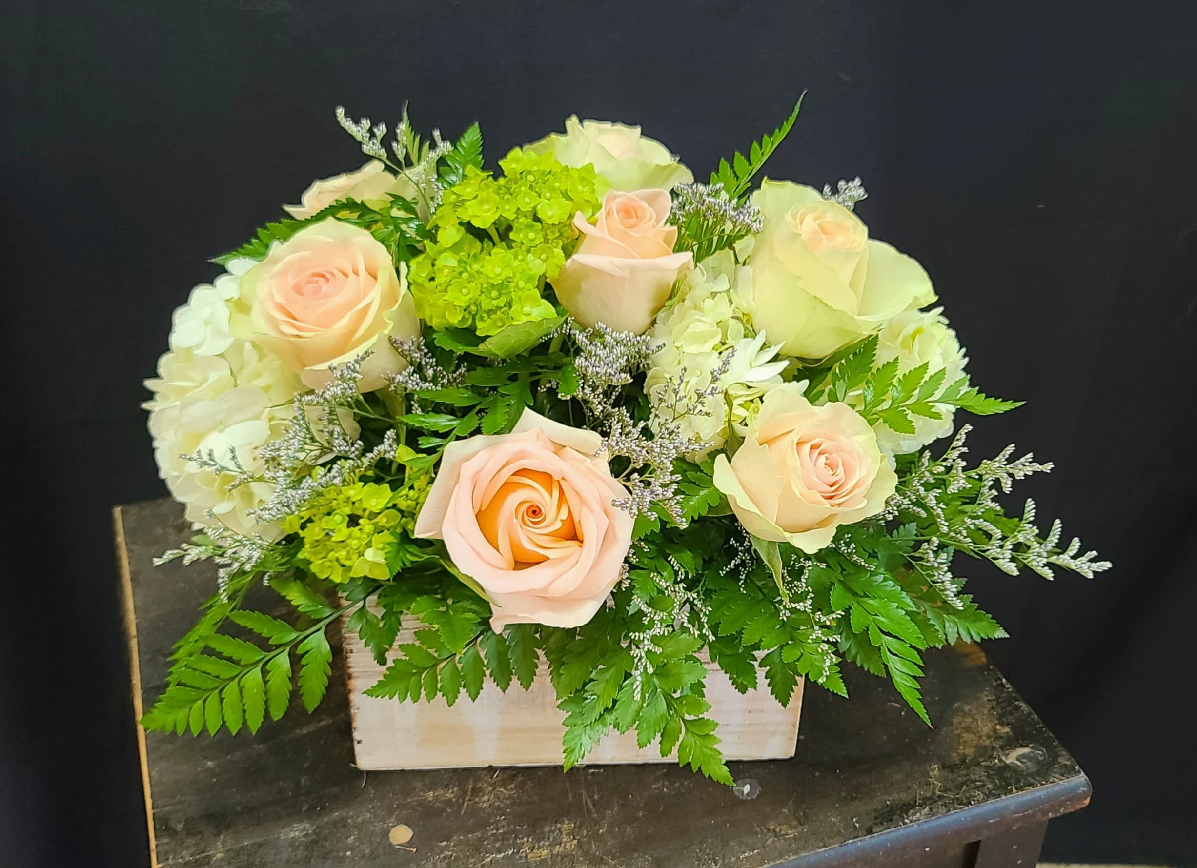 Peach roses and white hydrangeas in a wooden box