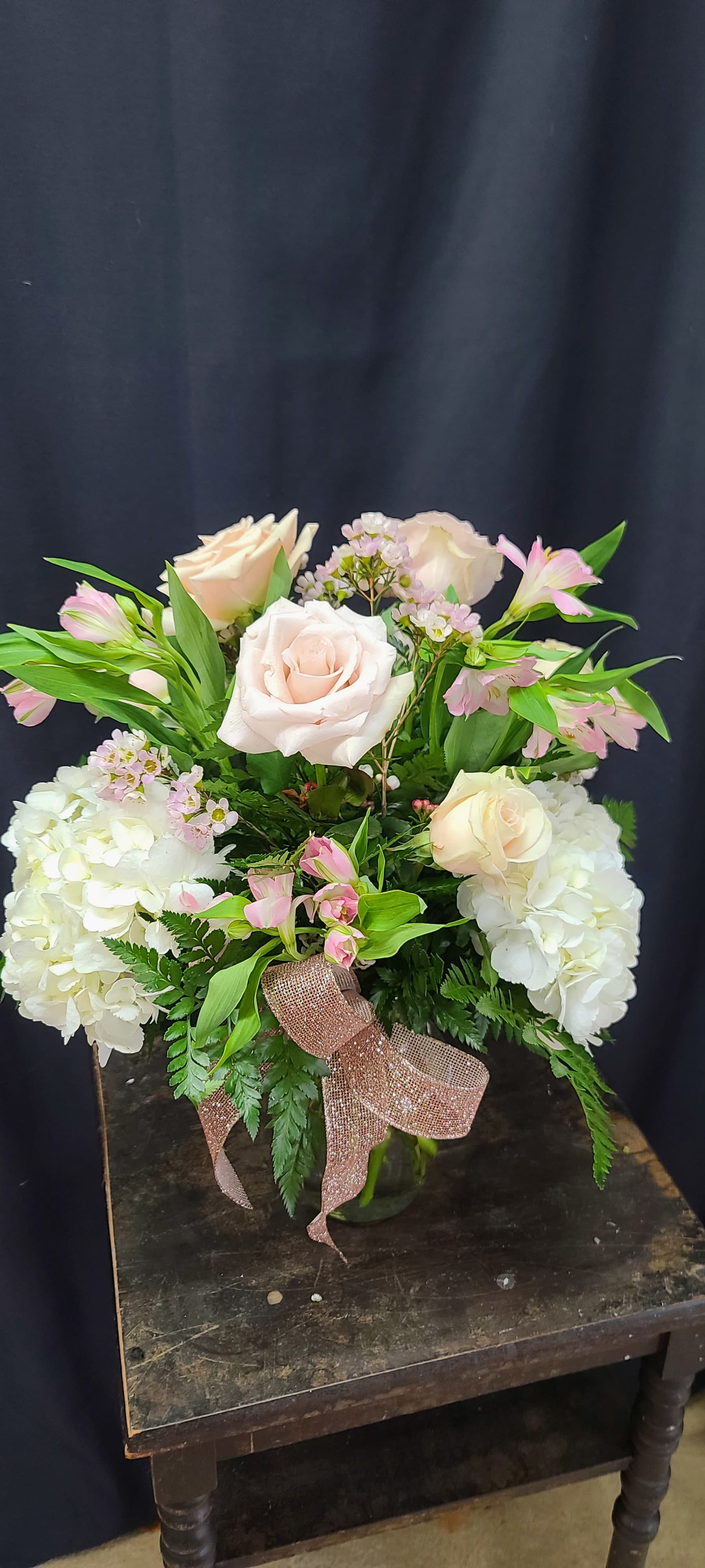 Pink and white roses arranged with hydrangeas in a glass vase