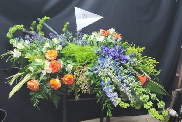 Large floral arrangement with orange roses and purple flowers