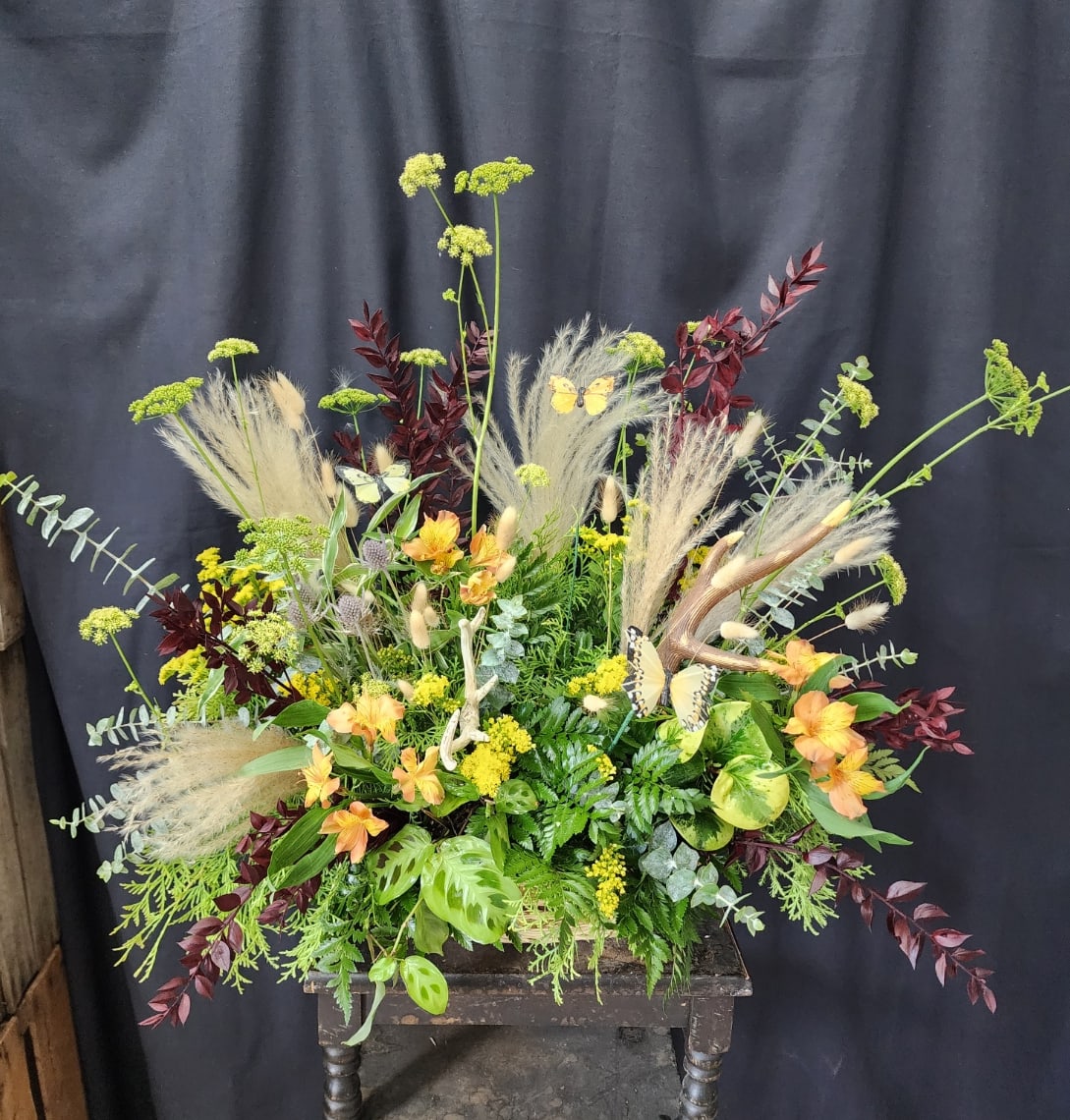 Large mixed floral arrangement with orange blooms and tall grasses