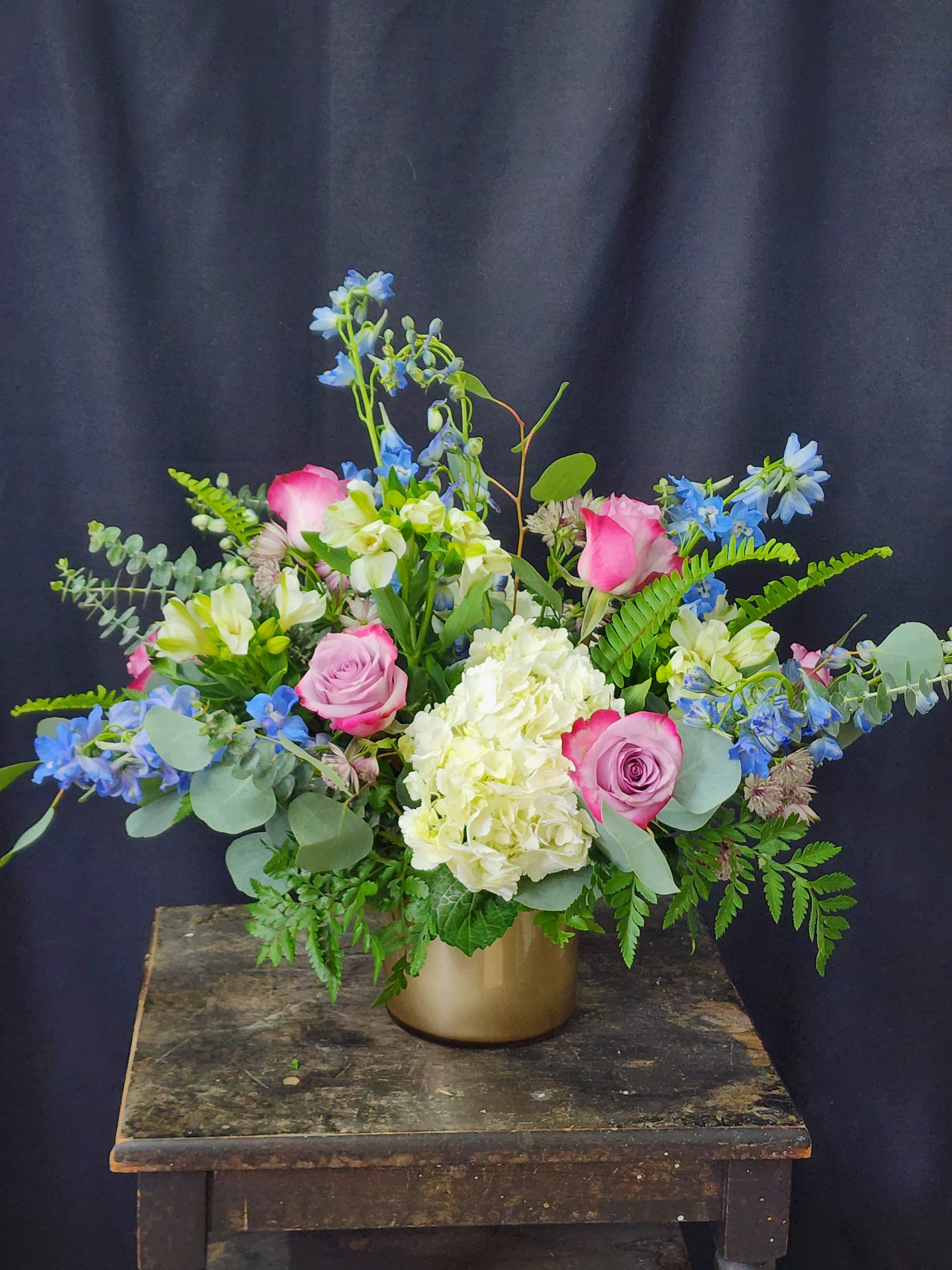 Pink roses and white hydrangea in a gold vase with blue flowers