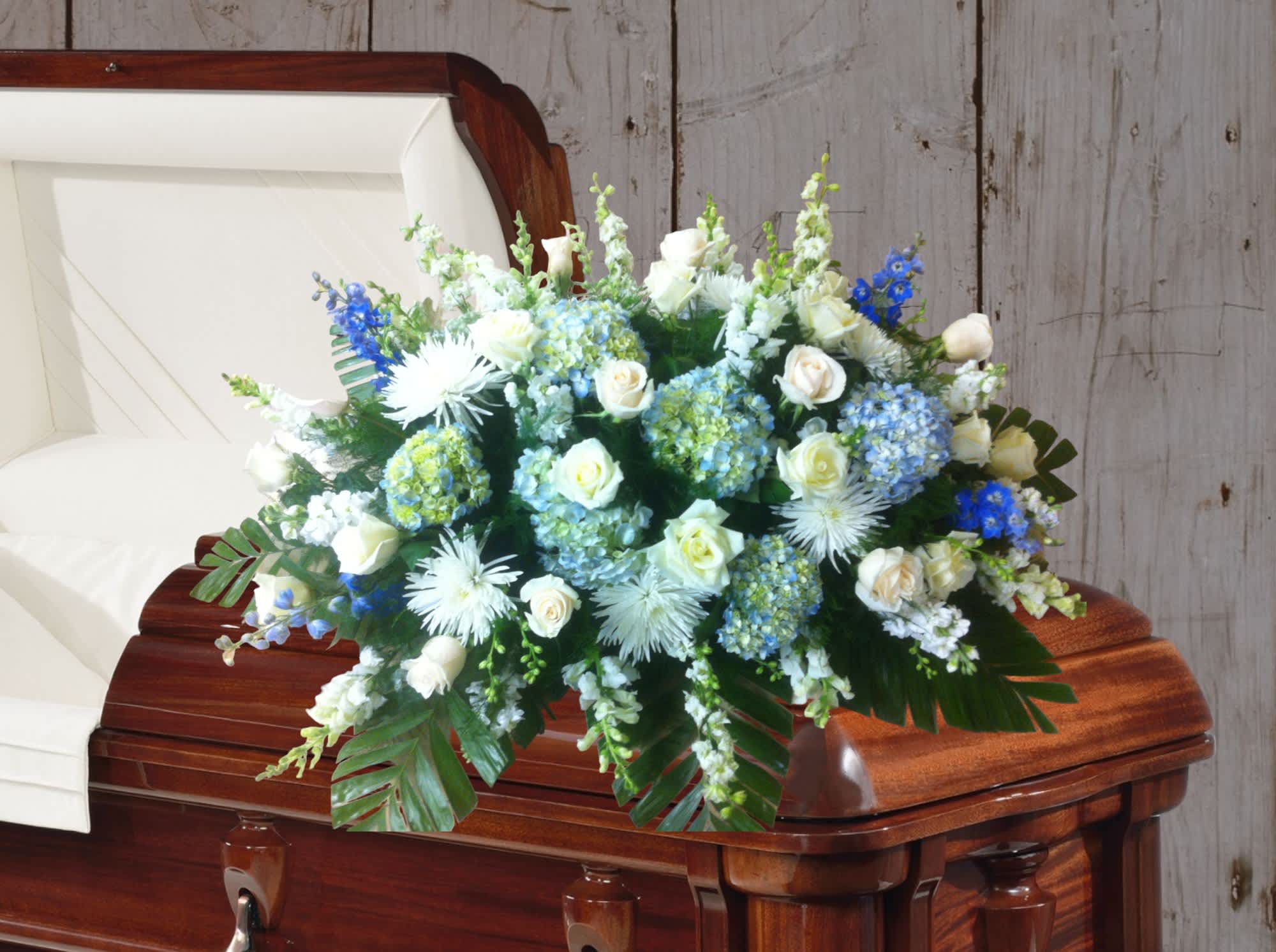 White and blue floral spray on a casket