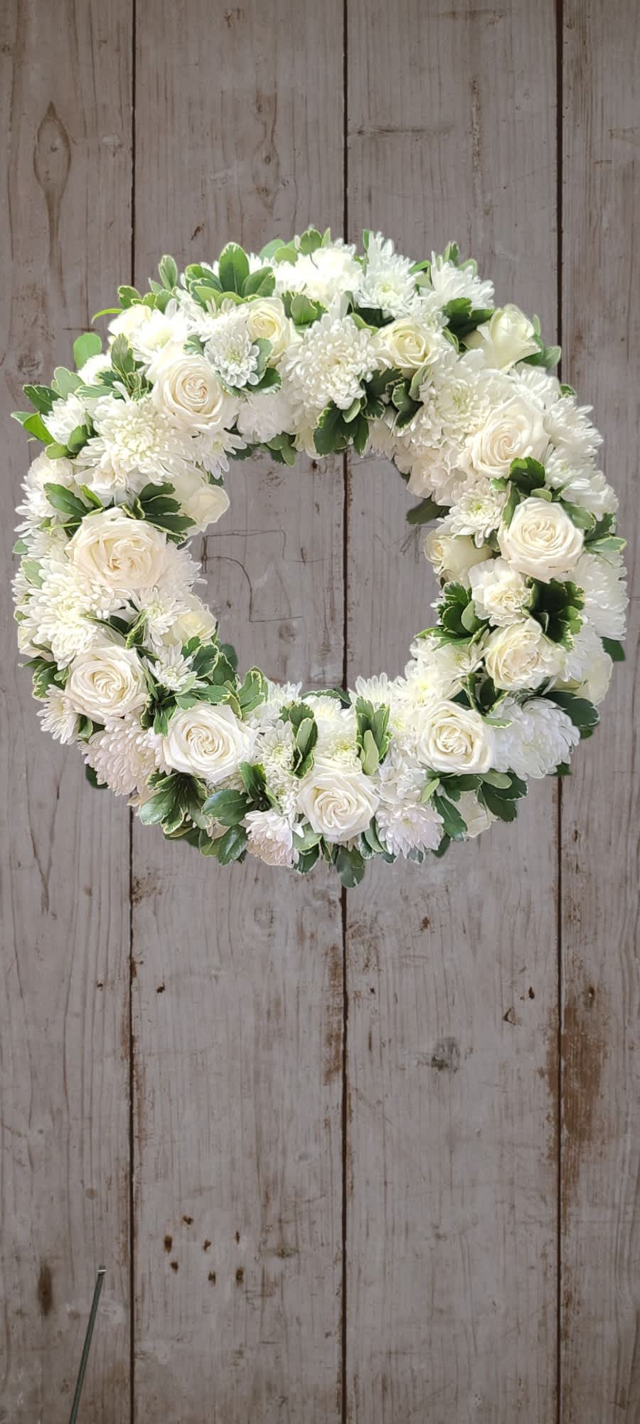White floral wreath with roses and chrysanthemums on a wooden background