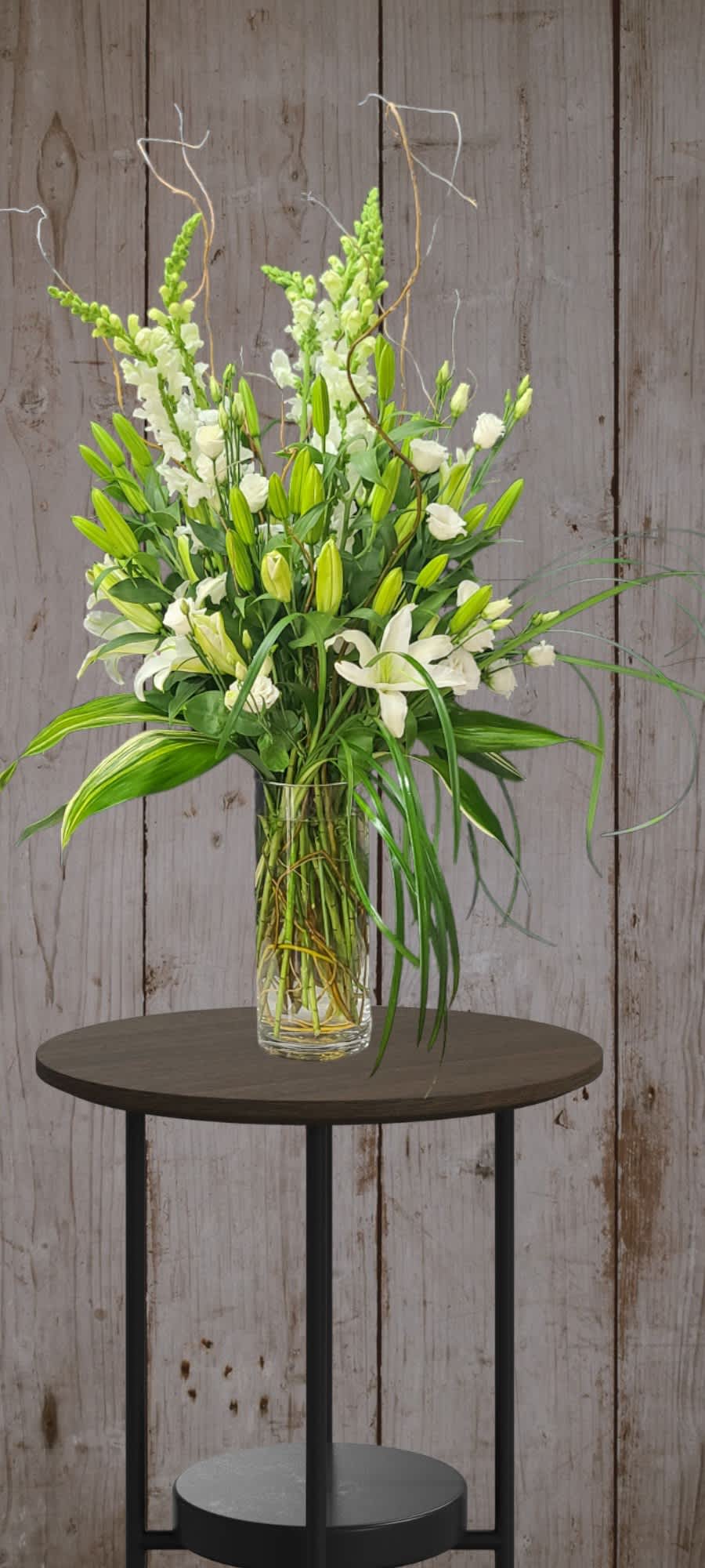 Tall white floral arrangement in a clear glass vase