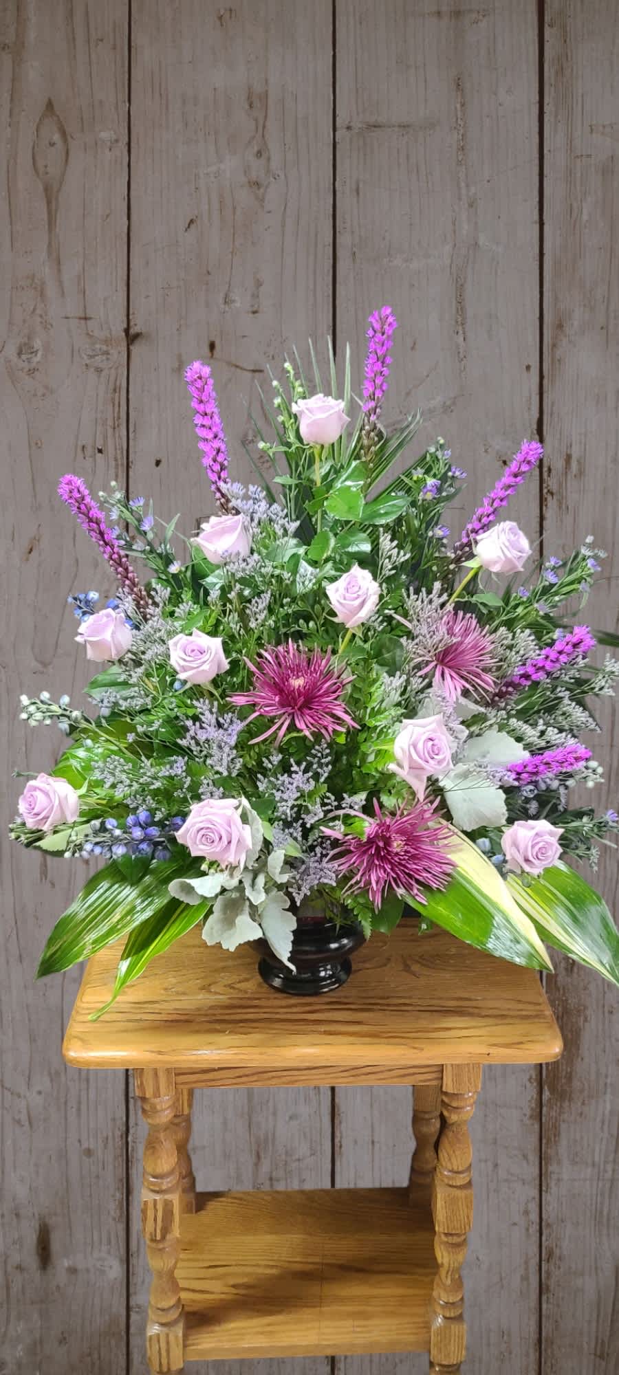 Lavender roses and purple flowers in a black vase