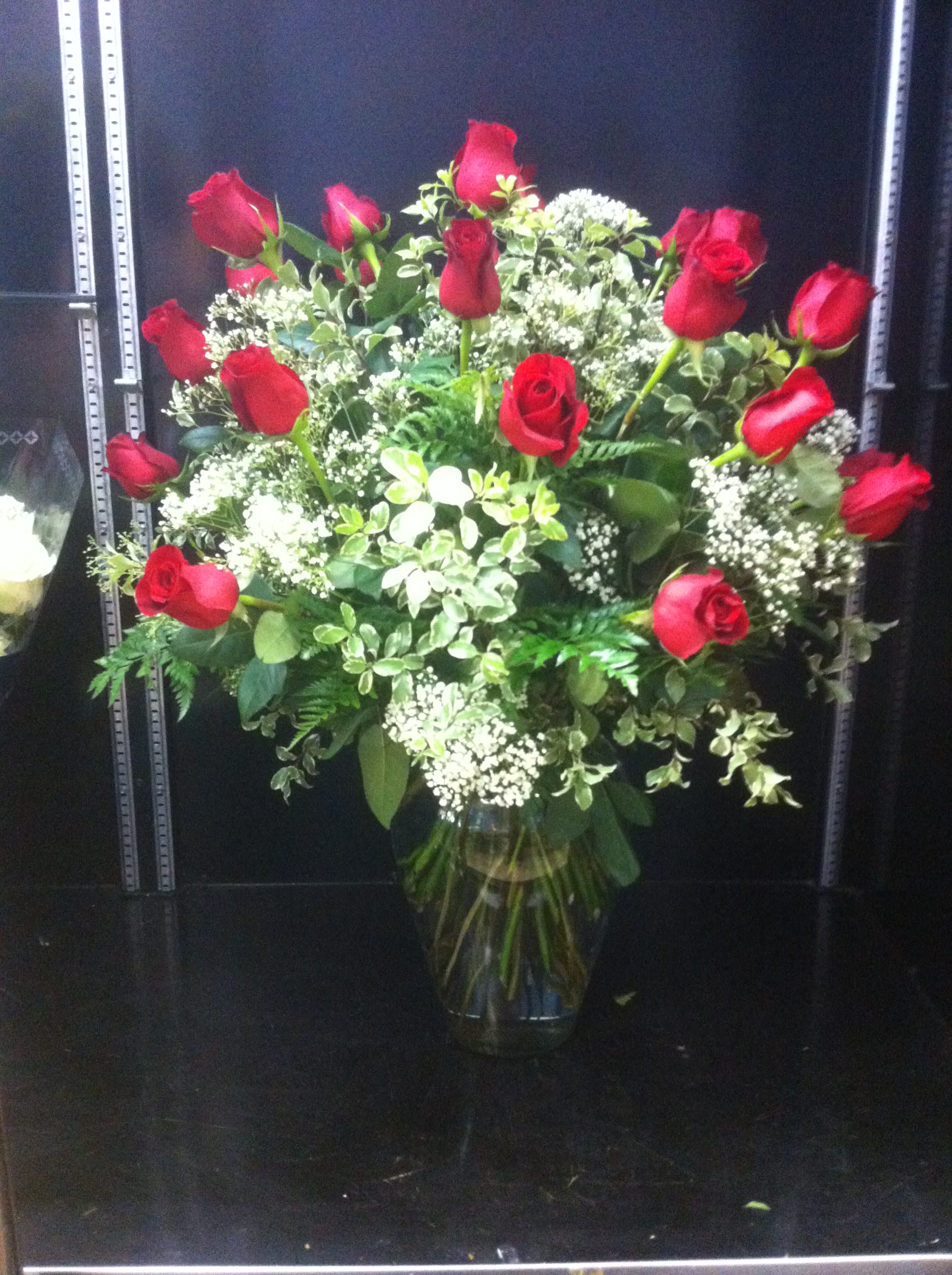 Red roses arranged in a clear glass vase with white filler flowers